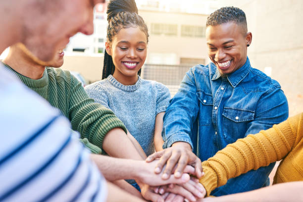 A diverse group of young people stacking their hands together in unity and teamwork